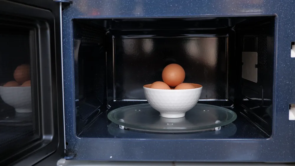 Tigela com ovos dentro de um forno micro-ondas, ilustrando o preparo de ovo cozido no micro-ondas de forma prática e rápida.